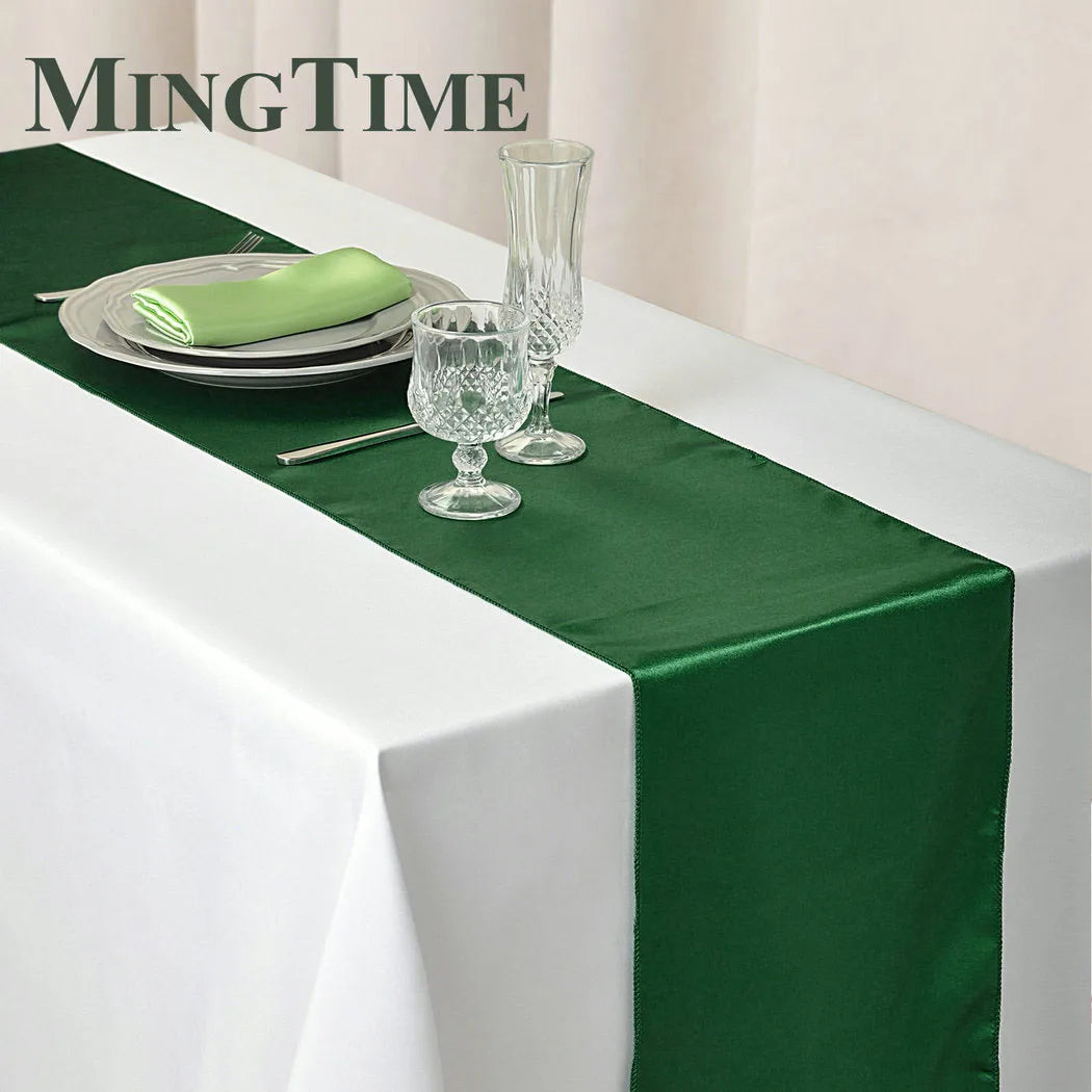 Elegant satin green table runner set with silverware and glassware on a white tablecloth