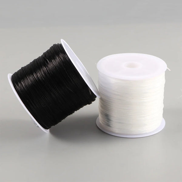 A spool of black flat elastic beading thread next to a roll of white flat elastic beading thread.