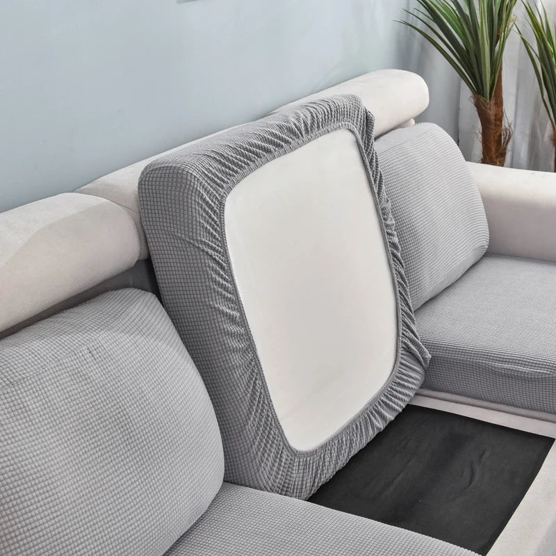 A gray stretch sofa seat cushion protector slipcover with a white insert and a textured fabric.