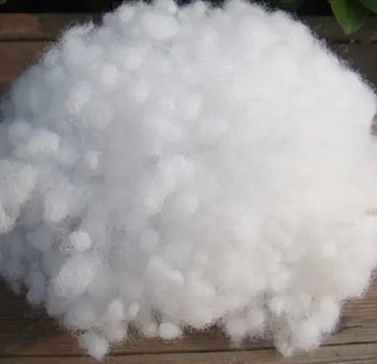 A pile of white, fluffy cotton batting used as a filler for crafting.