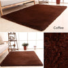 A dark brown plush throw rug displayed on a light wooden floor.