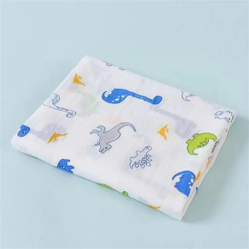 A white cotton muslin swaddle blanket featuring various blue and yellow animal designs.