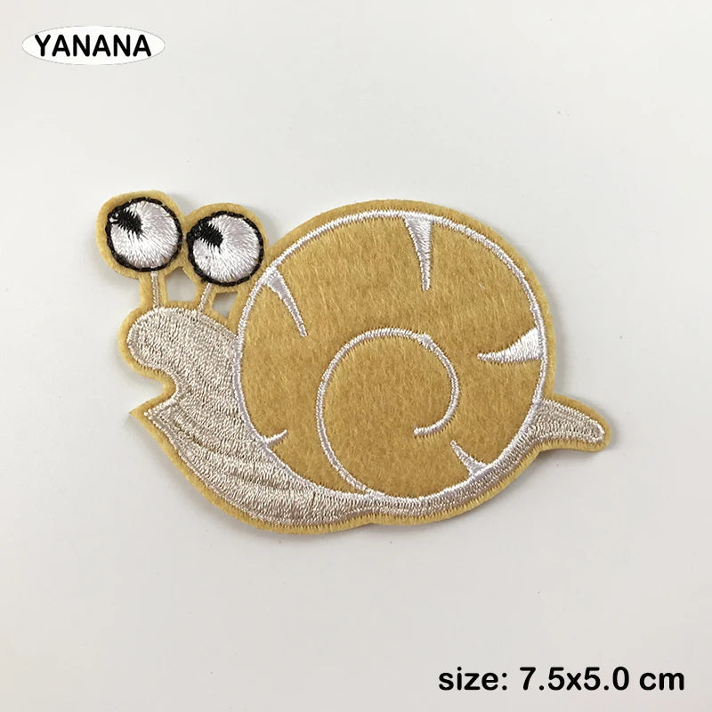 A tan embroidered patch of a sea turtle with large eyes and a spiral pattern.