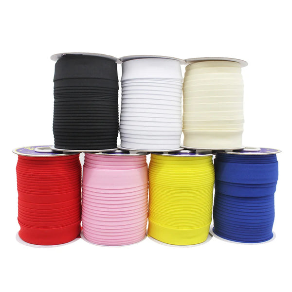 A collection of stacked bias tape binding ribbon in various colors including black, white, cream, pink, yellow, and blue.
