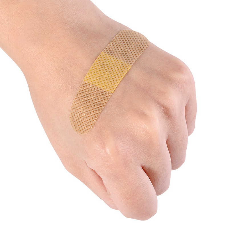 A hand shows a waterproof adhesive first aid plaster applied to the wrist.