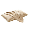 A smooth, beige satin pillowcase is draped and folded, showing its luxurious texture.