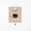 A beige iron-on patch featuring an embroidered black cat face with orange eyes and whiskers.