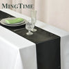 Elegant black satin table runner displayed on a white tablecloth with silverware and glassware.