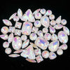 A collection of clear and iridescent silver claw rhinestones arranged in a circular pattern.