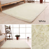 A white plush throw rug is displayed on a wooden floor, showing its soft texture and thickness.