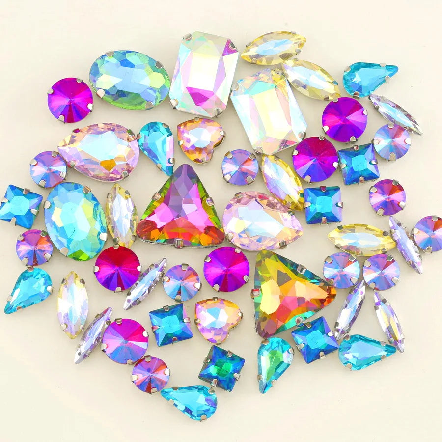 A collection of colorful silver claw rhinestones and gemstone-like decorations scattered on a white background.