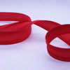 Red bias tape binding ribbon rolled into a loop on a white background.