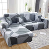 A gray and white geometric patterned L-shaped sofa protector cover lying on a wooden floor.