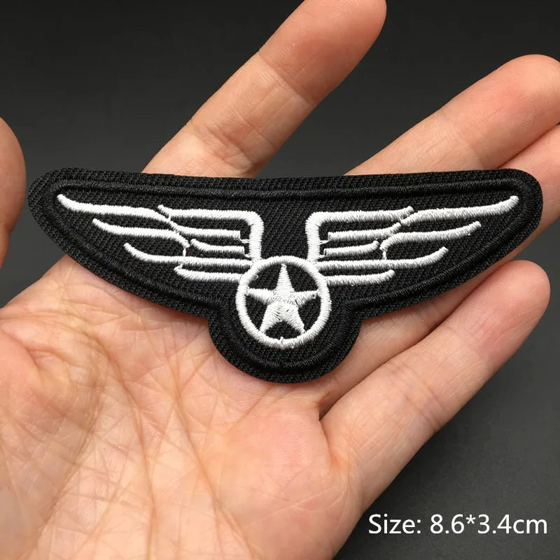 Black embroidered punk badge featuring white wings and a star design held in a hand