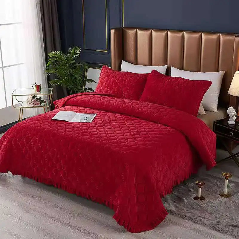 A vibrant red crystal velvet quilted bedspread is displayed on a bed with a tufted headboard.