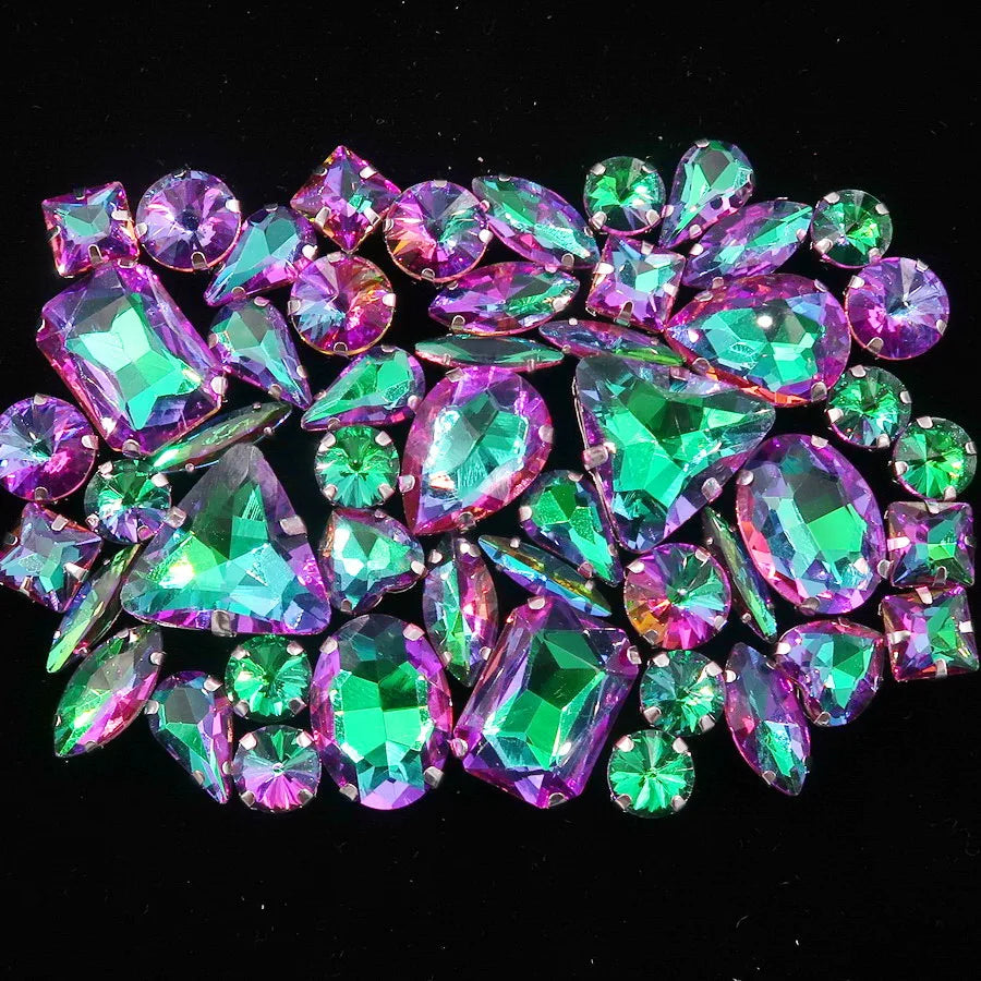 A close-up of a set of vibrant green and purple gemstone rhinestones arranged in a decorative pattern.