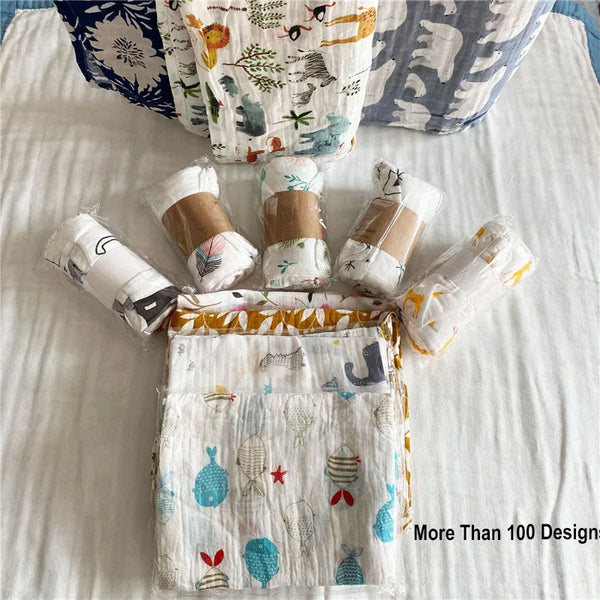 A collection of various patterned cotton muslin swaddle blankets displayed on a white surface.