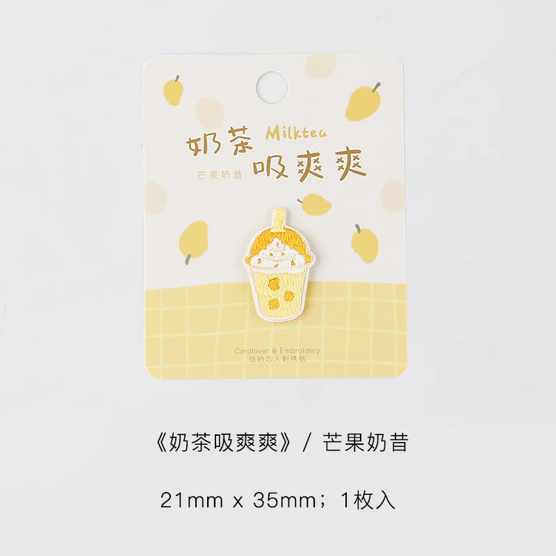 A yellow tag featuring an embroidered illustration of a cup of ice cream and surrounding yellow leaves.