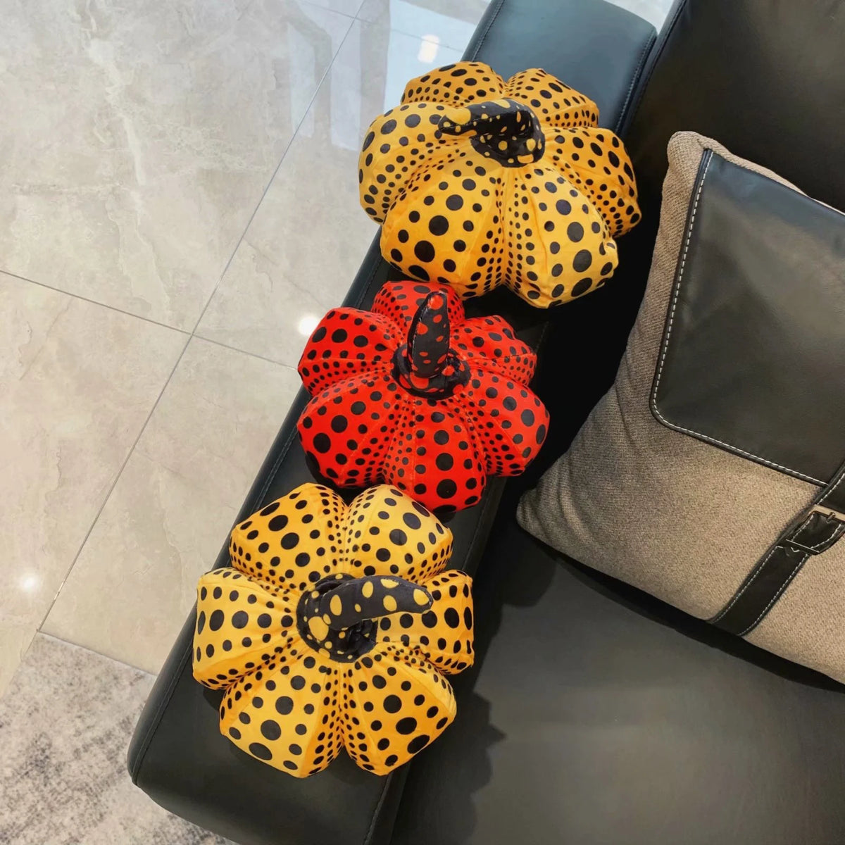 A collection of yellow and orange polka-dotted pumpkin plush cushions arranged in a line on a dark surface.