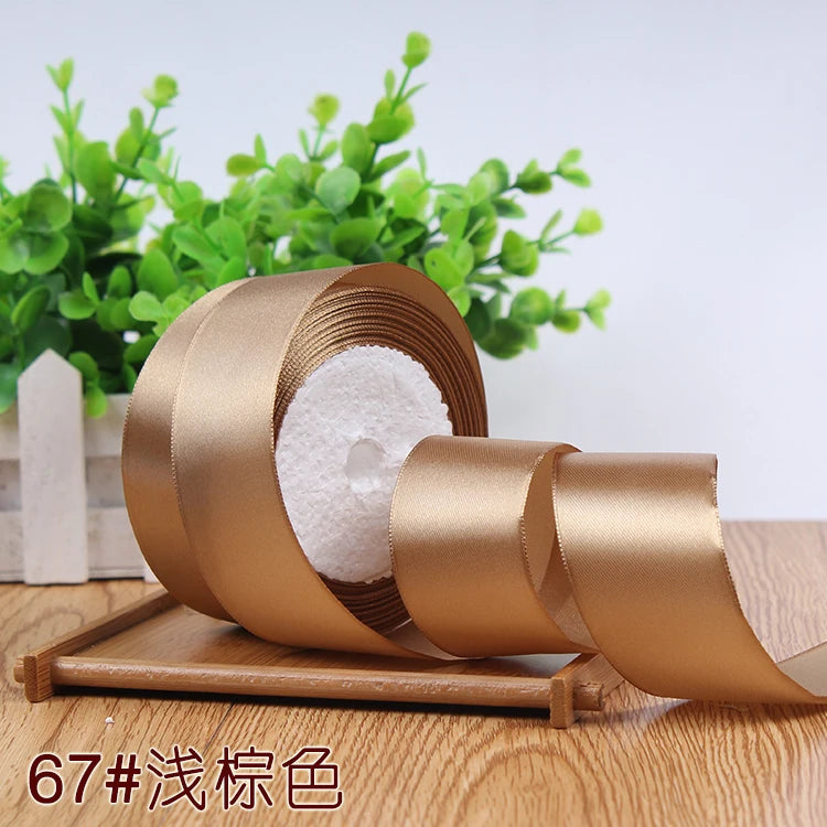 Roll of satin ribbon in a golden brown color with white filler, displayed on a wooden surface.