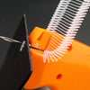 An orange clothing price tagging machine is shown with a metal pin being used to attach a white tag.