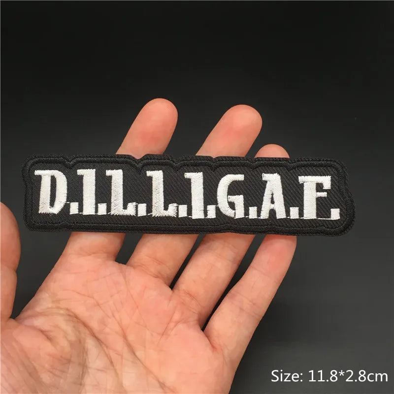 Black embroidered punk badge with the letters D.I.L.L.I.G.A.F. held in a hand