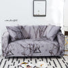 A gray sofa covered in a stretch floral elastic fabric featuring dark, abstract branch patterns.