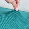 A hand is touching the textured teal fabric of a stretch sofa seat cushion protector slipcover.