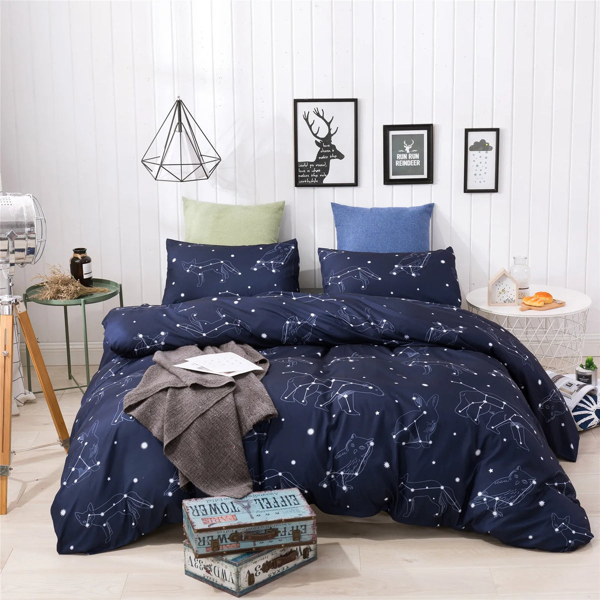 A navy blue duvet cover set featuring a starry sky pattern displayed on a bed in a bright room.