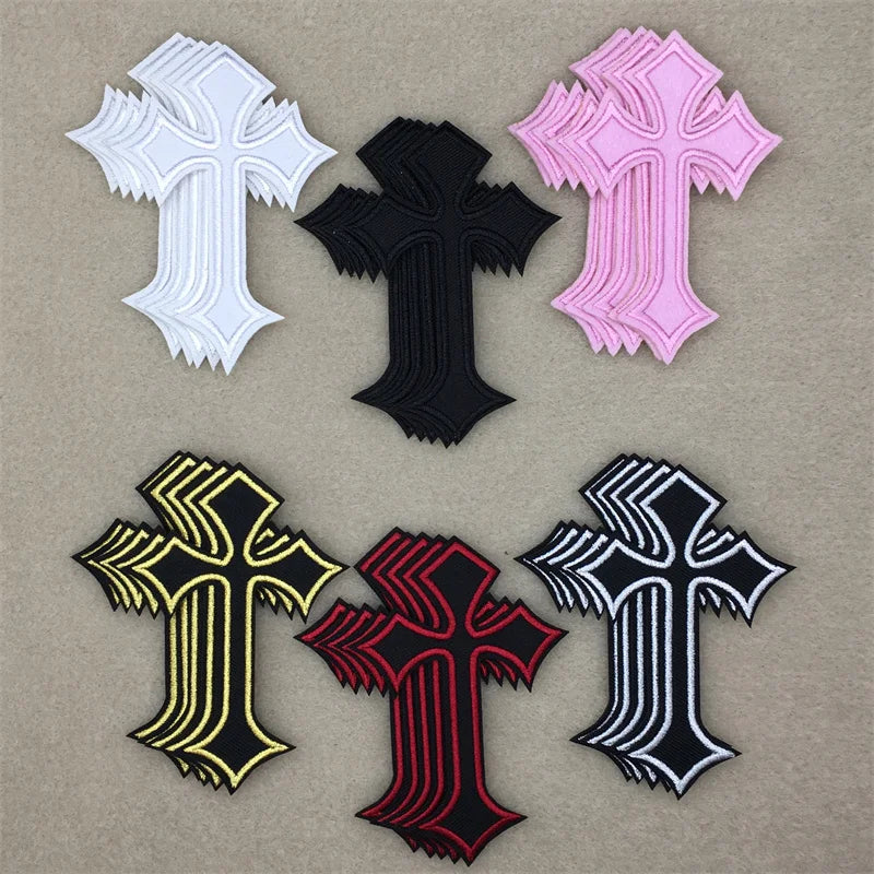 A collection of embroidered cross applique patches in white, black, pink, and black with yellow and red accents.