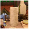 A large spool of natural hemp jute rope lying on a wooden surface with crafting tools and decorative items.