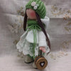 A handmade cotton toy filler batting doll with a green knitted hat and white clothing.