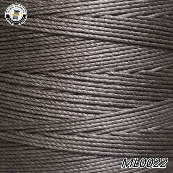 A close-up view of dark gray waxed thread embroidery cord with a label in the upper left corner.
