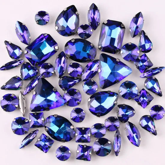 A collection of 50 iridescent blue and purple silver claw rhinestones scattered on a white background.