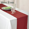 Elegant satin red table runner on a white tablecloth with silverware and glassware.