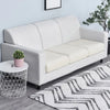 A modern light gray sofa with a cream seat cushion cover placed on a rug.