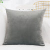 A square, solid gray velvet decorative cushion cover resting on a white surface.