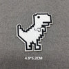 A white embroidered patch of a dinosaur silhouette on a gray fabric background.