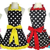 A display of various retro polka dot ruffle aprons in black and white with colorful ribbons.