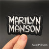 Black embroidered patch with white text MARILYN MANSON held by a hand