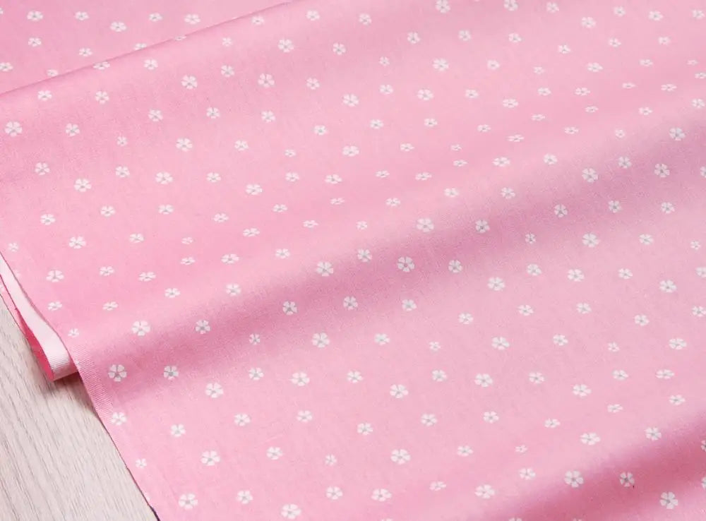 Pink floral and stripe cotton twill fabric rolled up, showing a light pink background with small white flowers.
