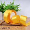 A roll of bright yellow satin ribbon for gift wrapping and DIY crafts resting on a wooden surface.