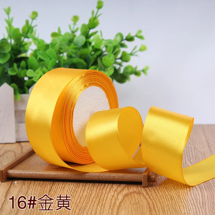 A roll of bright yellow satin ribbon for gift wrapping and DIY crafts resting on a wooden surface.