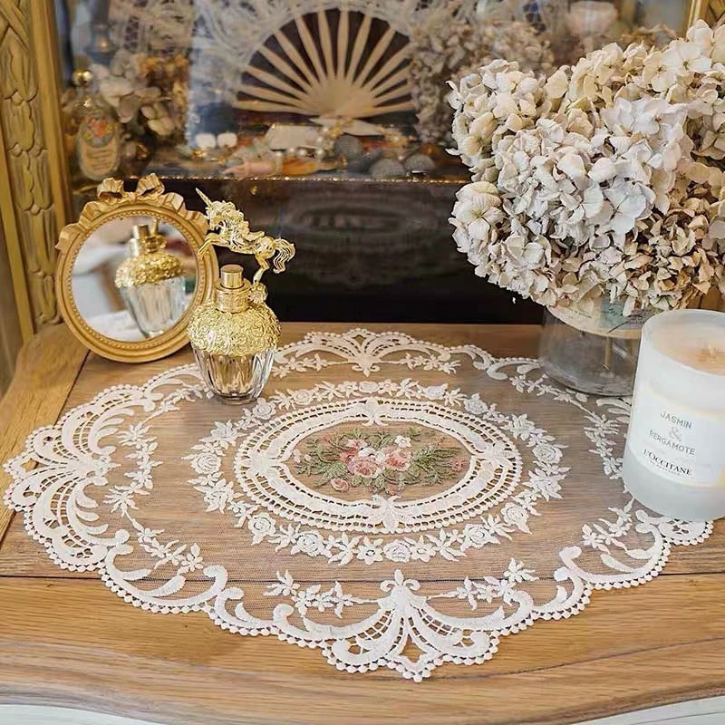 Elegant oval lace embroidered coaster set displayed on a wooden table with decorative items.