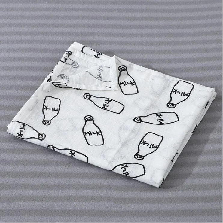A white muslin swaddle blanket featuring repeated black illustrations of milk bottles on a gray striped background.