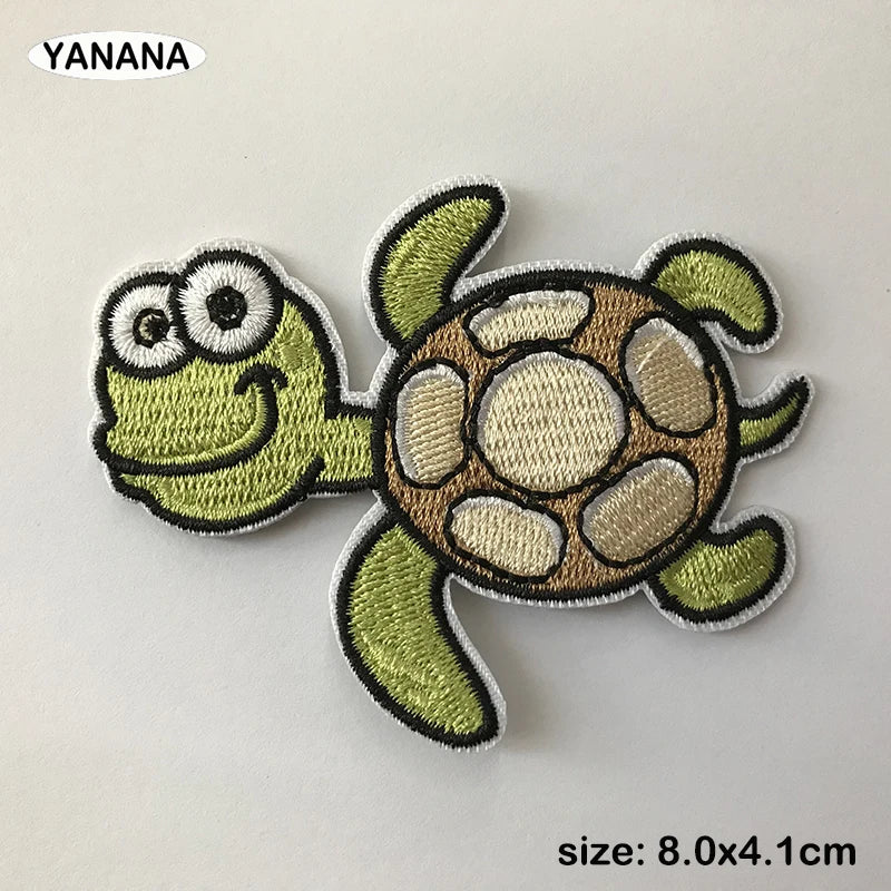 A green embroidered animal patch resembling a small lizard or gecko on a white background.