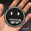 Black embroidered punk badge with a face and the text SHUT UP on a hand