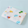 A white cotton muslin swaddle blanket featuring colorful animal designs like a yellow bird and green lizard.