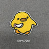 A yellow embroidered patch of a cartoon chick on a gray fabric background.