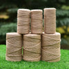 Five cylindrical rolls of natural beige hemp jute rope stacked on green grass